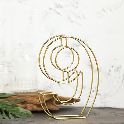 Gold abstract number 9 sculpture on a textured background.