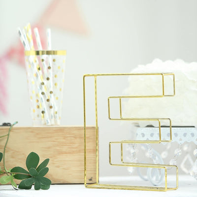 Gold geometric letter "S" decor piece on a plain background.