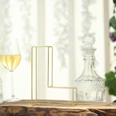Gold geometric letter "L" decor piece on a rustic wooden surface.