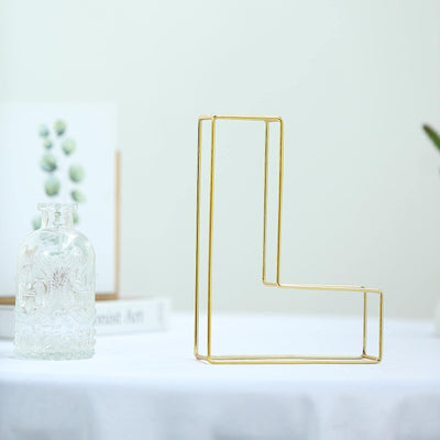 Gold geometric letter L decor on a white table.