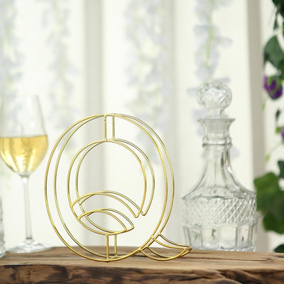 Gold wire letter Q decor with a leaf design, set against a blurred background.