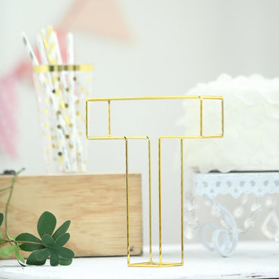 Gold letter "T" paper clip holder on a desk with decorative elements.
