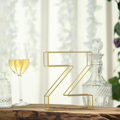 Gold wire letter "Z" decor piece on a wooden surface with a glass of wine.