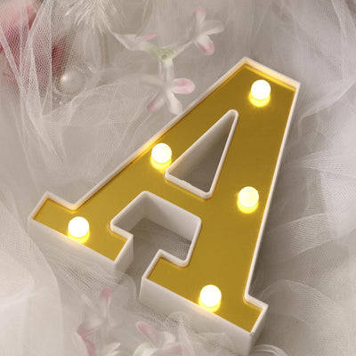 Gold letter A marquee sign with LED lights on soft tulle background.