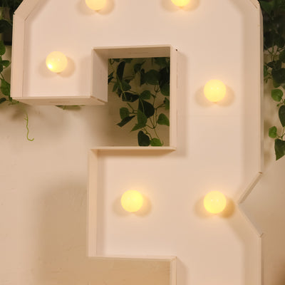 Light-up marquee number three with round bulbs and greenery backdrop.