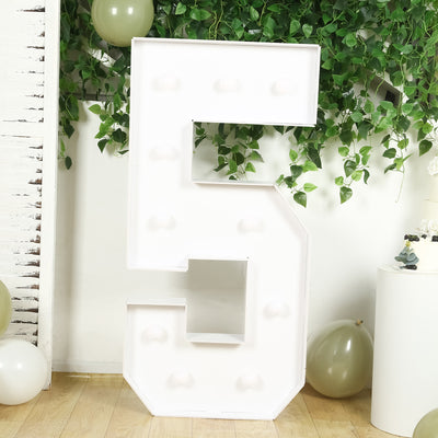 White marquee number five with light bulbs on a plain backdrop.