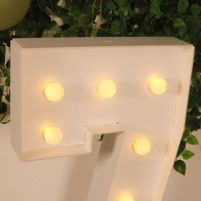 Decorative marquee letter with warm LED lights on a green backdrop.