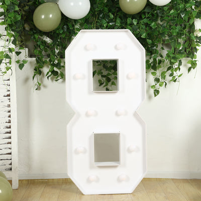 Large white marquee number 8 with light bulbs against greenery backdrop.