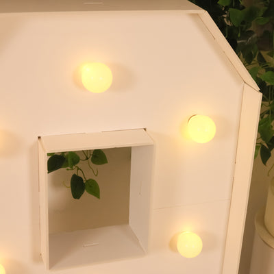 Decorative light-up house with glowing bulbs and an open window.