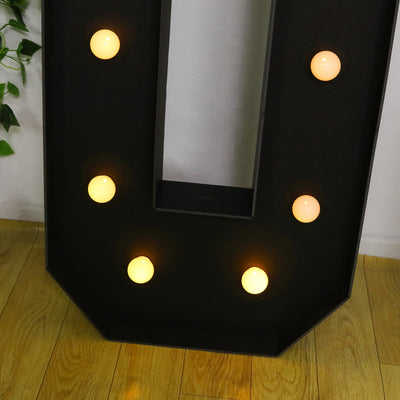 Black marquee letter "U" with warm glowing bulbs