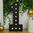 Black marquee number 1 with lights and greenery party backdrop
