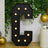 Large black marquee letter "C" with lights, set against a greenery backdrop.