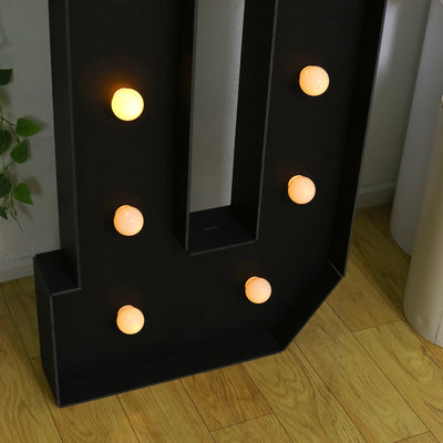 Decorative vintage marquee letter with glowing bulbs.
