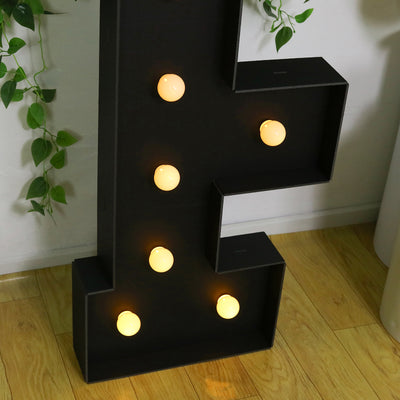Black marquee number "1" with glowing bulbs on a wooden floor.