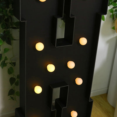 Decorative light-up letter with warm bulbs on a dark background.