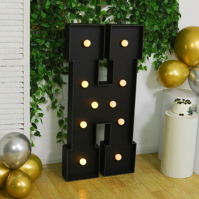 Large illuminated letter "H" decor with gold and silver balloons