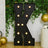 Black marquee letter "K" with lights against greenery and gold balloons.