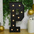 Large illuminated letter P with decorative lights, set against a greenery backdrop.