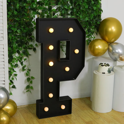 Black marquee letter "P" with lights, decorated in a festive setting.