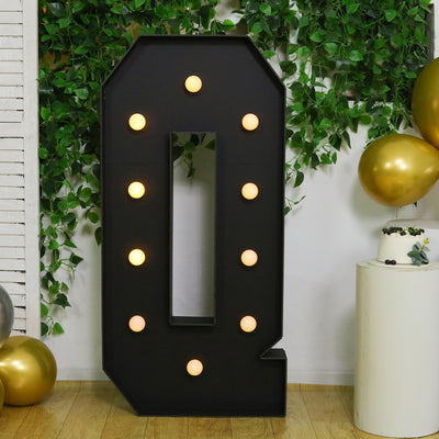 Large black marquee number "0" with lights, surrounded by greenery and balloons.
