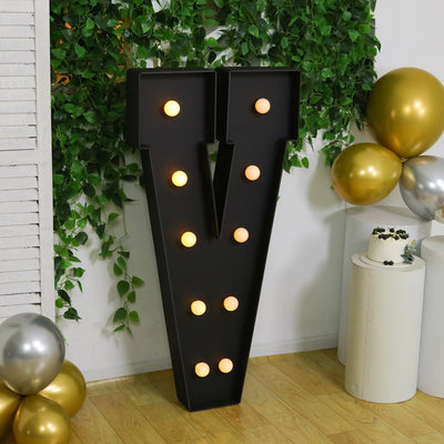 Large decorative letter "V" with lights, set against a festive backdrop.