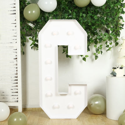 White marquee letter "C" with lights, decorated with greenery and balloons.