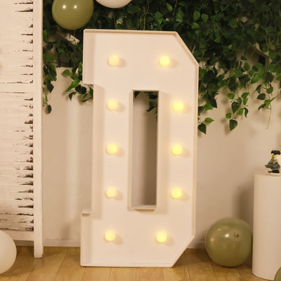 Illuminated decorative letter "D" with lights on a green backdrop.