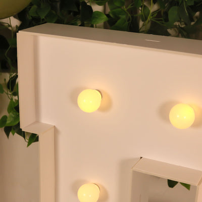Illuminated marquee letter with bulbs on a plain backdrop