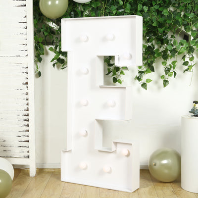 White marquee letter "E" with light bulbs, styled with greenery and balloons.