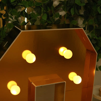 Decorative marquee letter with warm lights and gold finish.