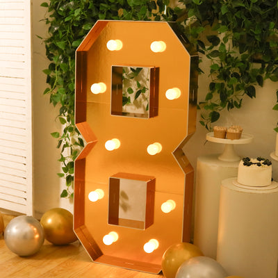 Decorative mirrored number 8 with lights in a festive setting.