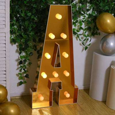 Gold mirrored letter "A" marquee sign with lights, set in a festive scene.