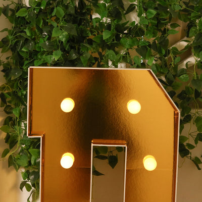Gold marquee number one with lights, surrounded by greenery.