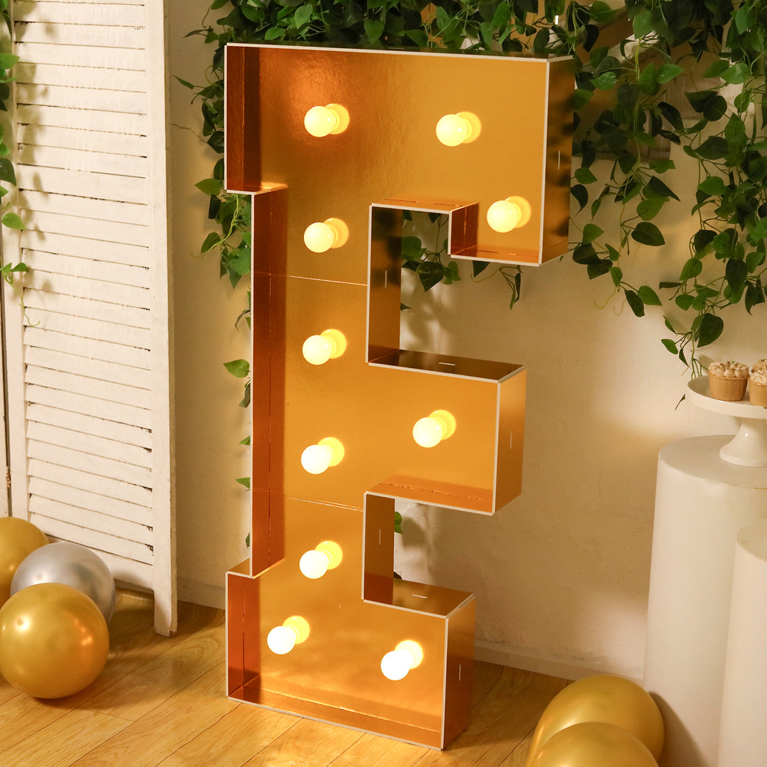 Gold decorative letter E with lights in a festive setting.