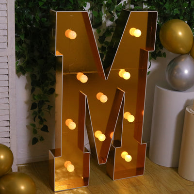 Illuminated gold letter "M" marquee sign with lights.