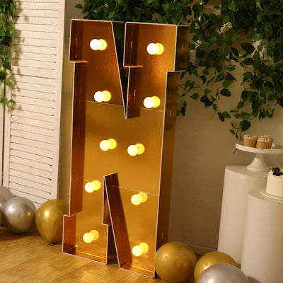 Gold marquee letter "N" with lights, perfect for events or decor.