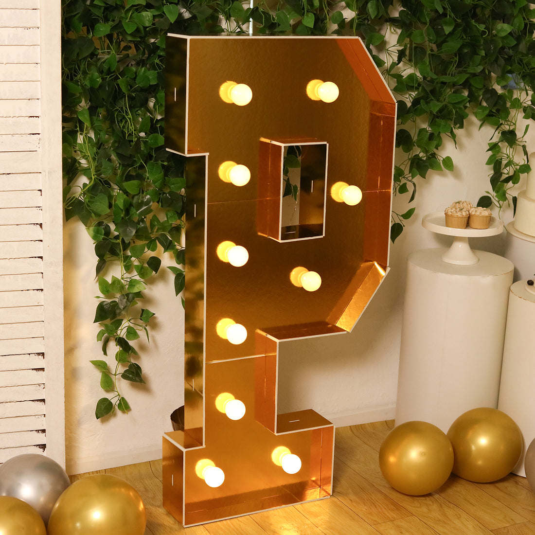 Gold marquee letter P with lights in a festive setting.
