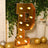Gold marquee letter P with lights in a festive setting.