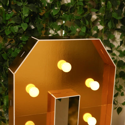 Gold mirror marquee letter with light bulbs, perfect for decor.