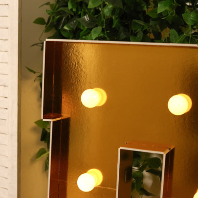 Gold letter marquee with light bulbs against a green plant backdrop.