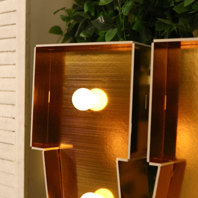 Stylish copper lamp with illuminated bulbs against a plain background.