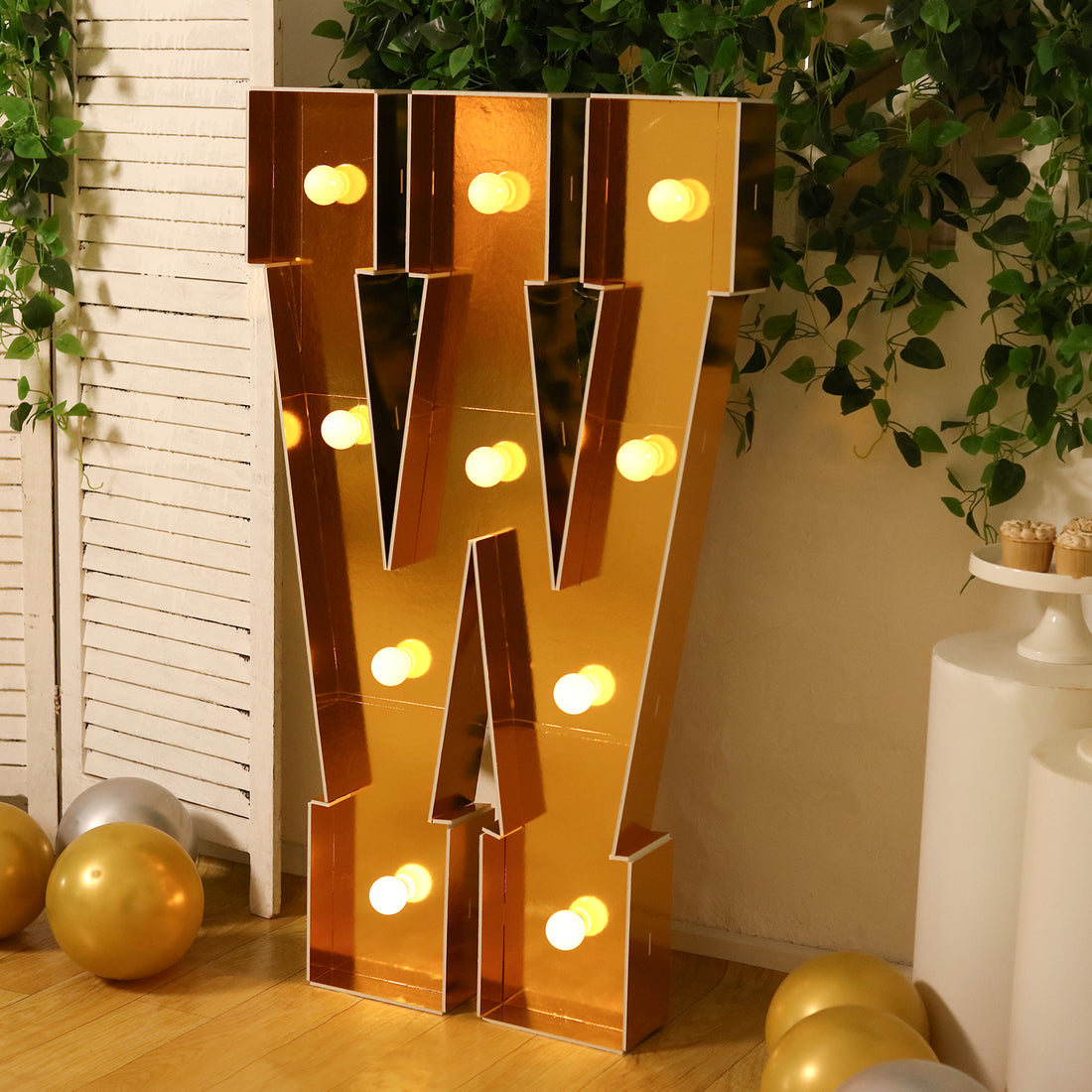 Gold marquee letter "W" with lights, set in a festive atmosphere.
