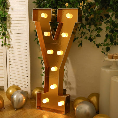 Golden letter "Y" marquee sign with lights, surrounded by balloons.