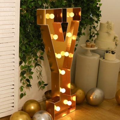 Gold marquee letter V with lights at a wedding dessert display