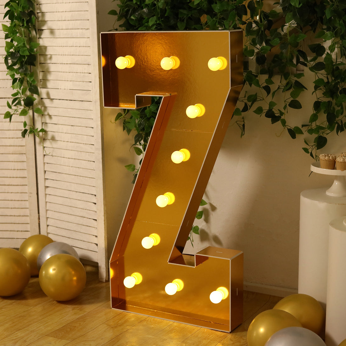 Gold marquee letter 'Z' with lights, styled in a festive setting.