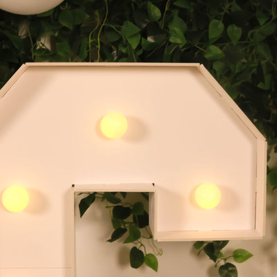 Decorative light fixture with round bulbs on a plant backdrop.
