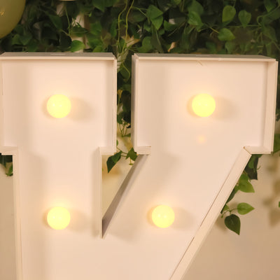 Illuminated decorative letter V with bulbs on a green backdrop.