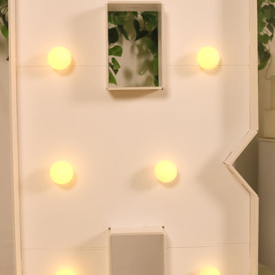 Lighted marquee letter "B" with bulbs on a plain backdrop.