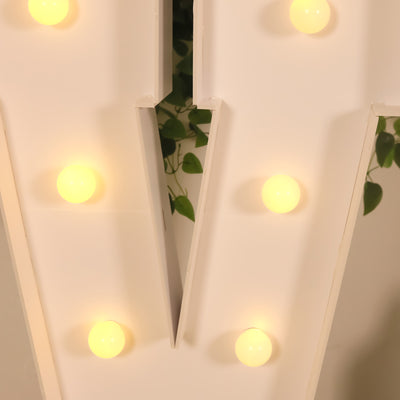 Decorative light-up letter "V" with glowing bulbs on a neutral background.