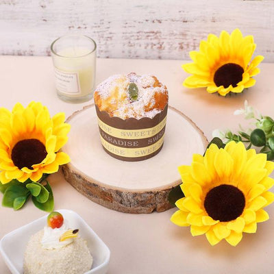 Delicious muffin on a wooden slice with sunflowers and cream.